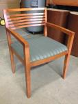 Used Guest chair with medium tone veneer finish and greenish fabric 